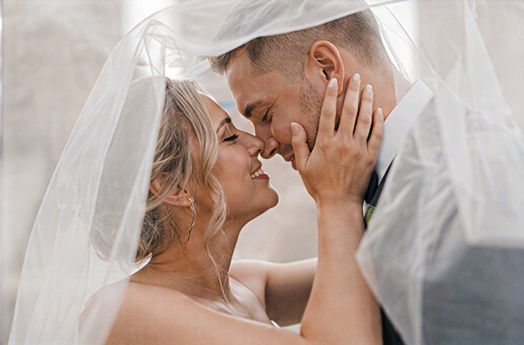 Bride and groom sharing a kiss beneath her veil