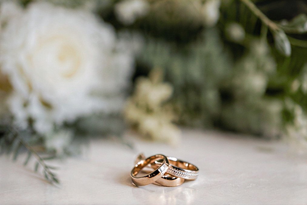 Wedding rings beside soft white flowers